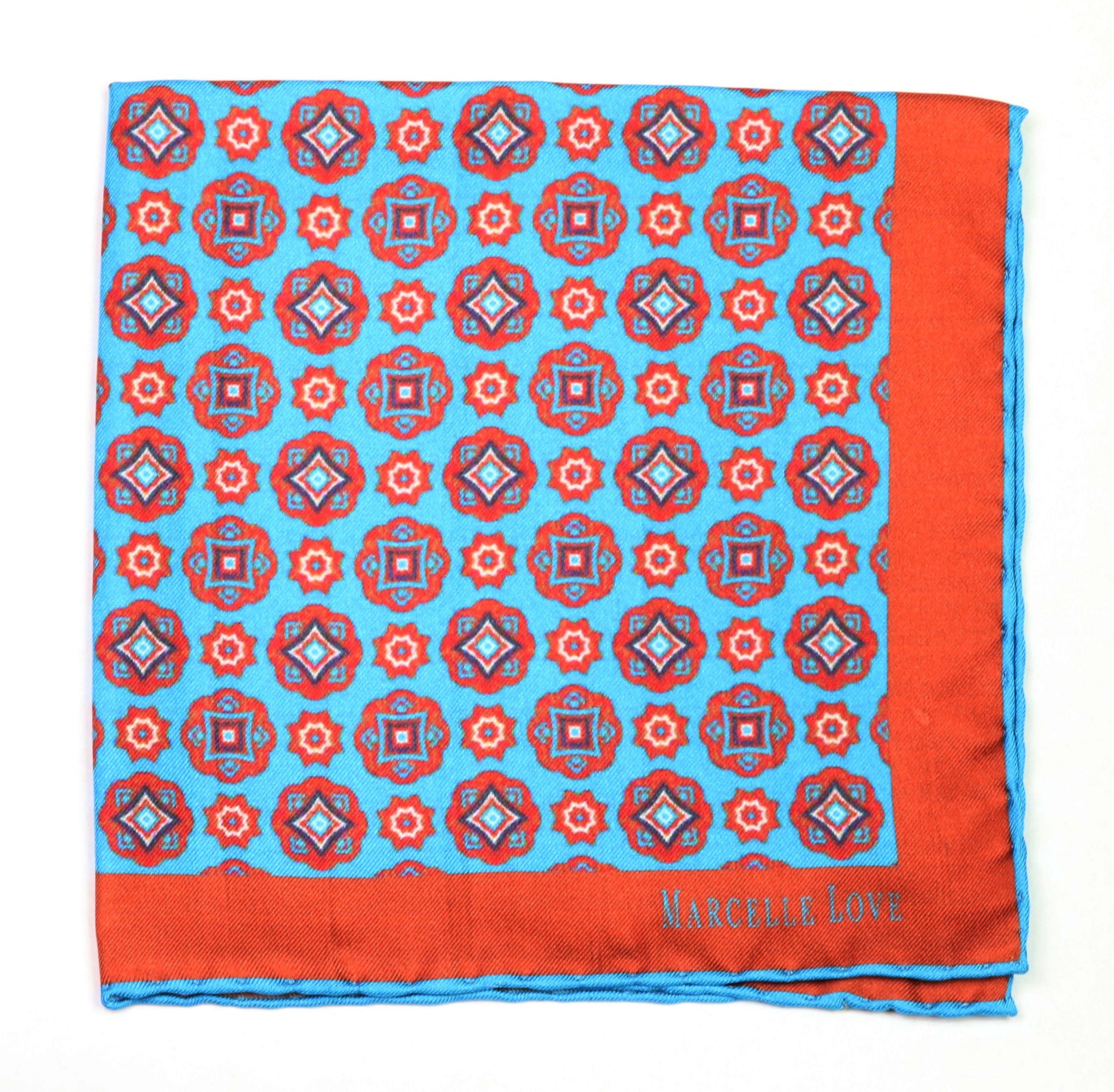 A pocket square with a floral and diamond pattern, predominantly red and blue, with the brand name 'MARCELLE LOVE' printed at the lower right corner.
