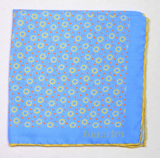 A blue pocket square with a white floral and dot pattern, and 'MARCELLE LOVE' printed at the lower right corner.